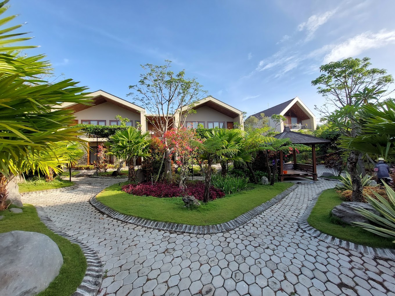 Gambar halaman hotel tradisional Jawa dengan taman yang rimbun.