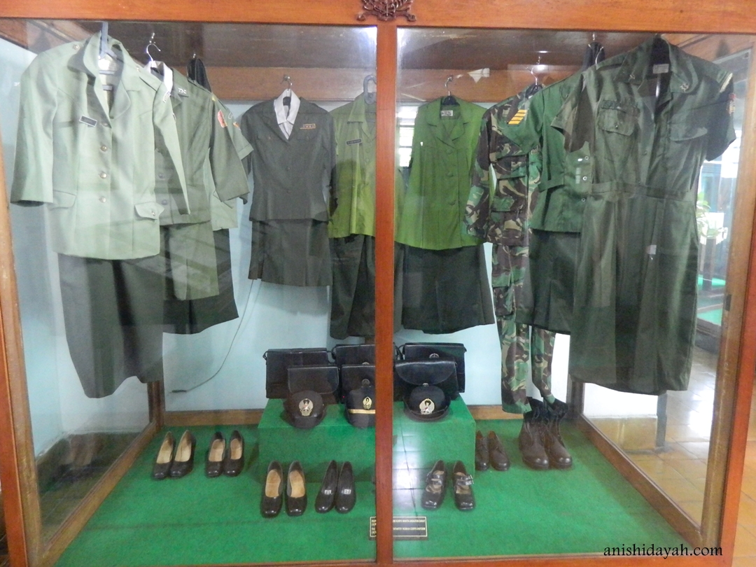 Gambar interior museum sejarah dengan pajangan senjata dan seragam lama.