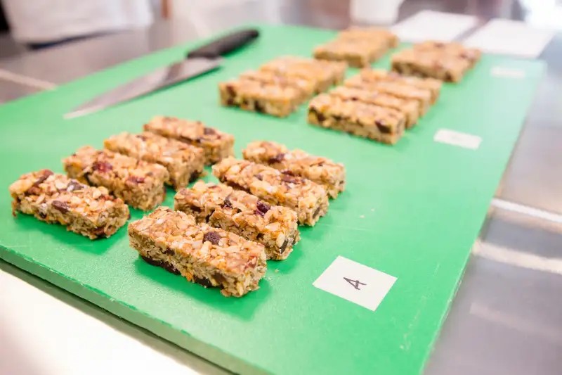 Gambar beberapa sereal batangan dengan kemasan yang menunjukkan biji-bijian dan buah kering.