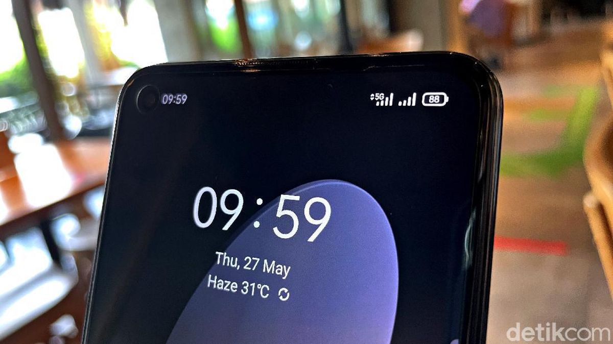 Layar ponsel menampilkan ikon sinyal jaringan penuh dengan latar belakang gelombang jaringan digital.