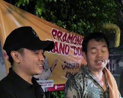 Gerobak nasi goreng di pinggir trotoar yang sedang melayani antrean pembeli di malam hari.
