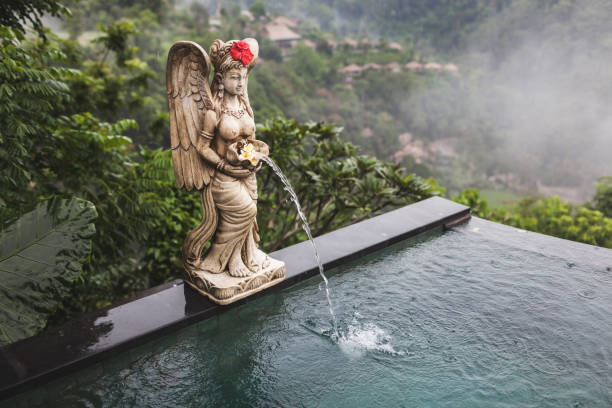 Gambar kolam renang yang didekorasi seperti reruntuhan kuno dengan air terjun buatan dan patung-patung.