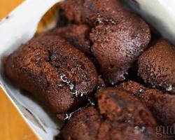 Beberapa potong kue balok dengan isian cokelat yang meleleh keluar, disajikan di atas piring.