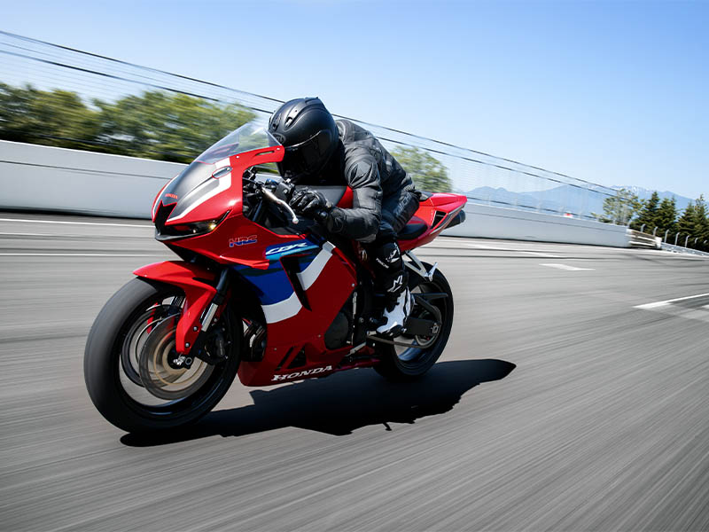 Gambar Honda CBR600RR di lintasan balap atau jalan pegunungan yang berkelok-kelok, menonjolkan kecepatan dan desain supersport agresifnya.