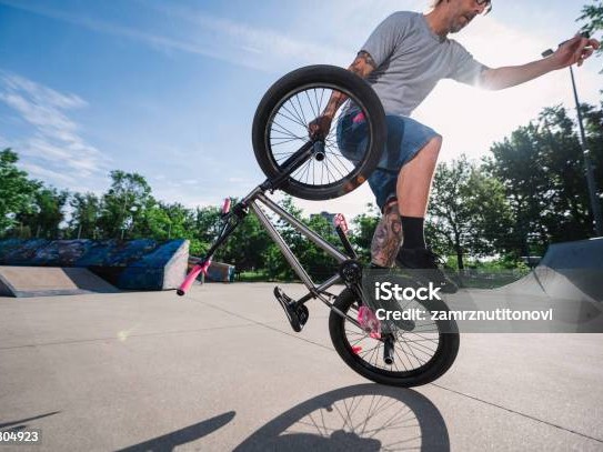 Gambar sepeda BMX GT Performer di udara saat melompat di taman skate, dengan pengendara beraksi, menonjolkan kemampuan freestyle-nya, dengan latar belakang samar Jakarta Timur.