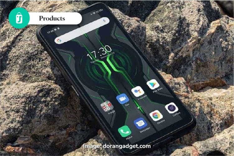 Ponsel rugged (tahan banting) yang terlihat terkena percikan air di lingkungan luar ruangan yang berdebu.