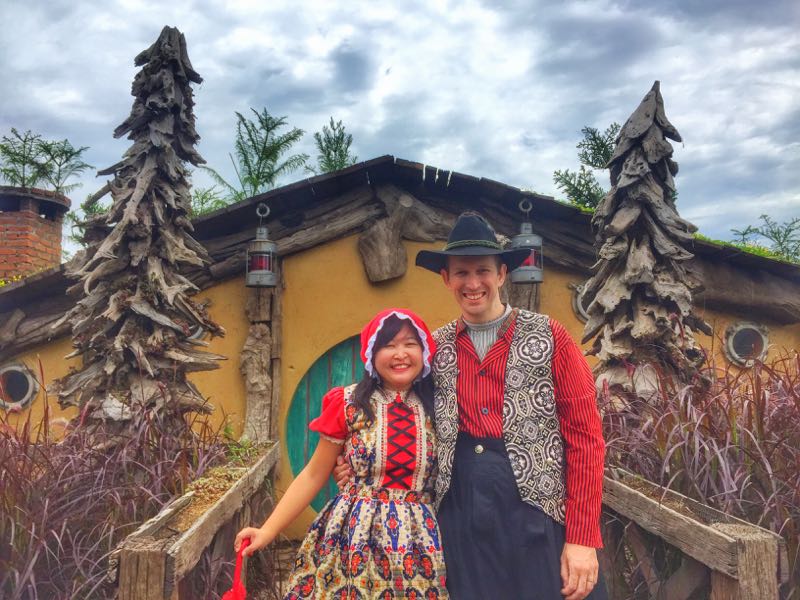 Keluarga sedang berfoto di depan rumah Hobbit di Farmhouse Lembang.
