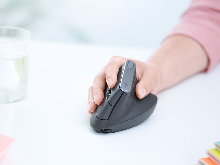 Gambar mouse vertikal ergonomis berbentuk unik, dipegang oleh tangan dalam posisi alami, tegak, menonjolkan desain yang berorientasi pada kenyamanan.