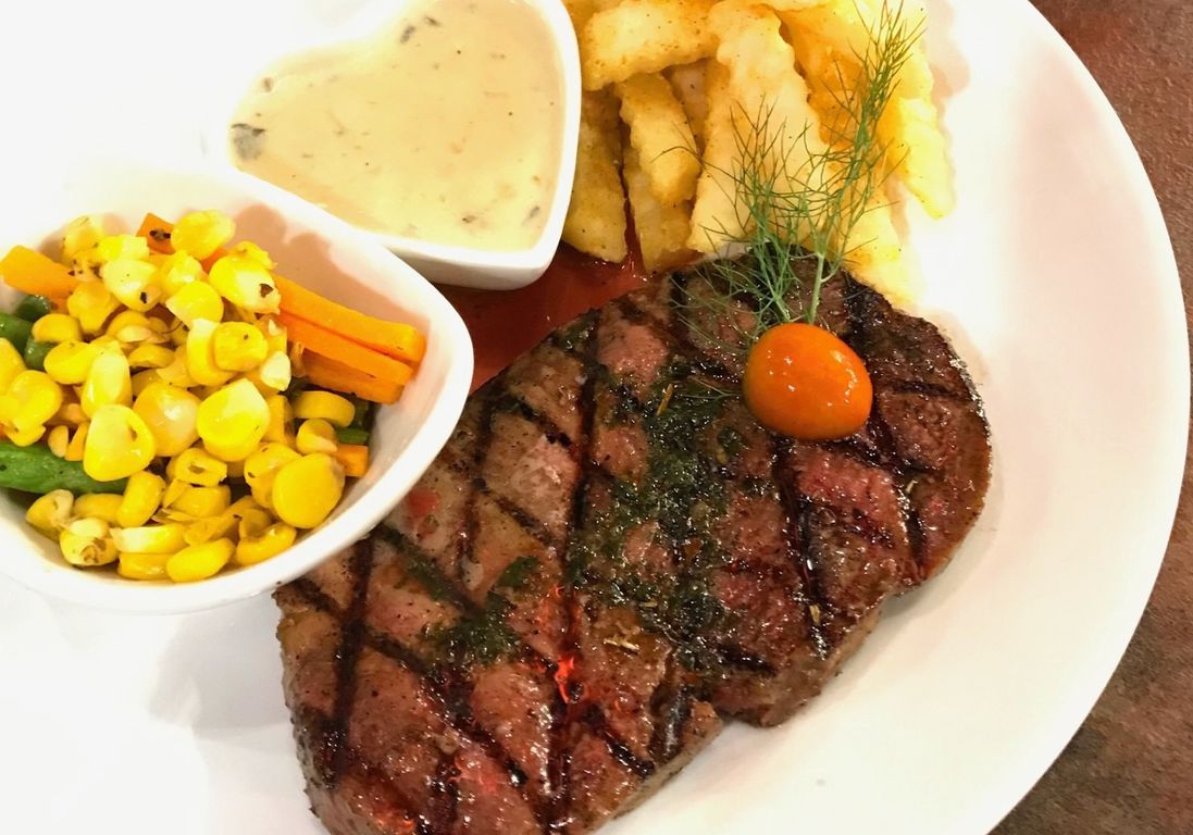 Hidangan steak dengan garnish yang cantik di meja restoran yang modern.