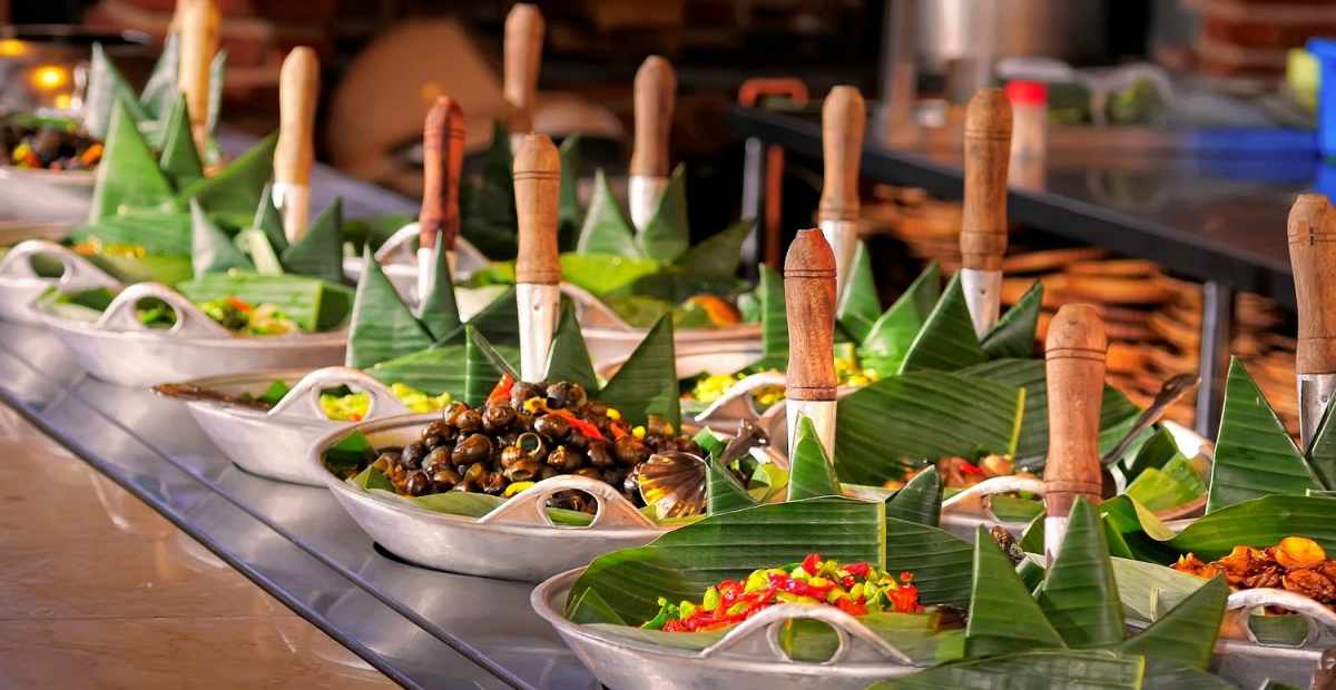 Meja lesehan di restoran Sunda dengan hidangan nasi timbel komplit, ayam goreng, ikan asin, dan lalapan.