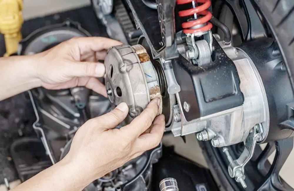 Mekanik sedang memeriksa mesin motor matic di sebuah bengkel resmi.
