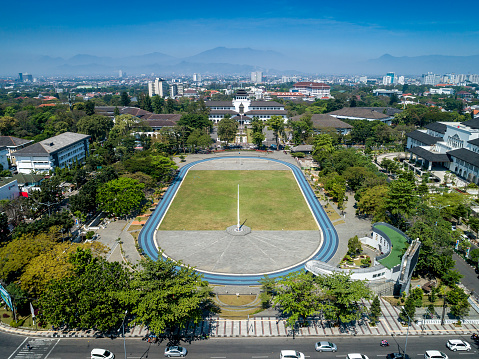 Orang-orang jogging di area Gasibu Field dengan latar belakang Gedung Sate.