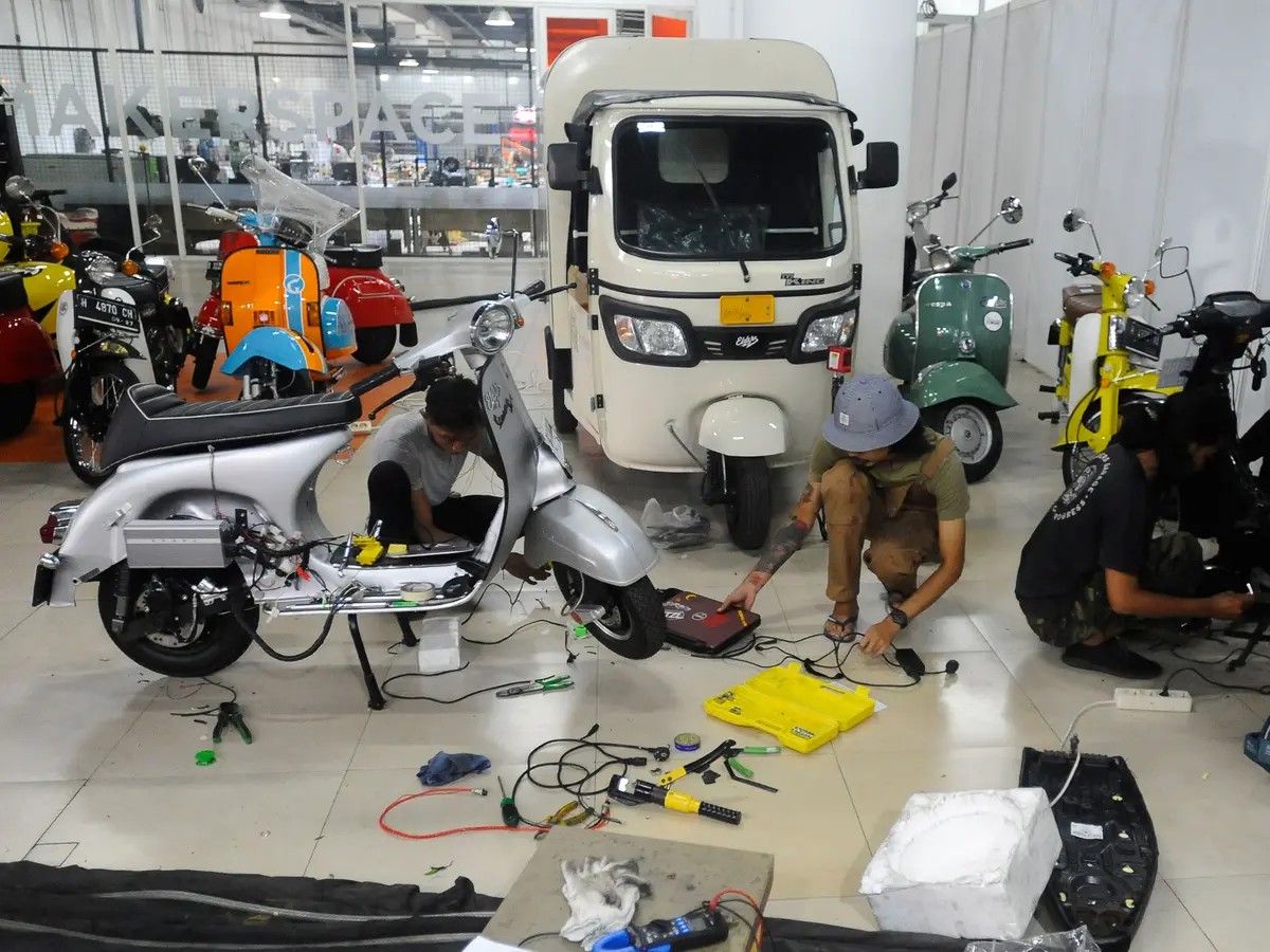 Gambar bengkel yang mengkhususkan diri pada konversi motor listrik, dengan motor listrik yang dipajang dan teknisi sedang bekerja.