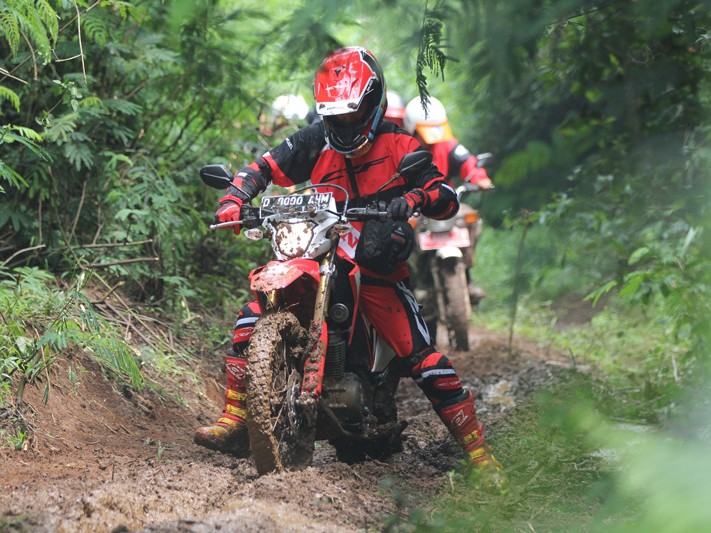 Gambar Honda CRF150L di jalan tanah dengan latar belakang alam yang indah (misalnya, hutan atau bukit) dekat Bandung, menekankan kemampuan off-road-nya.