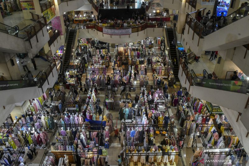 Suasana keramaian di dalam mall dengan toko-toko dan pengunjung.