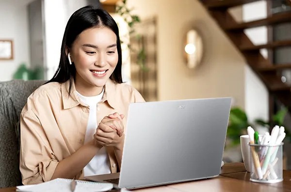 Seorang pelajar sedang menggunakan smartphone untuk belajar, dengan buku dan laptop di meja.