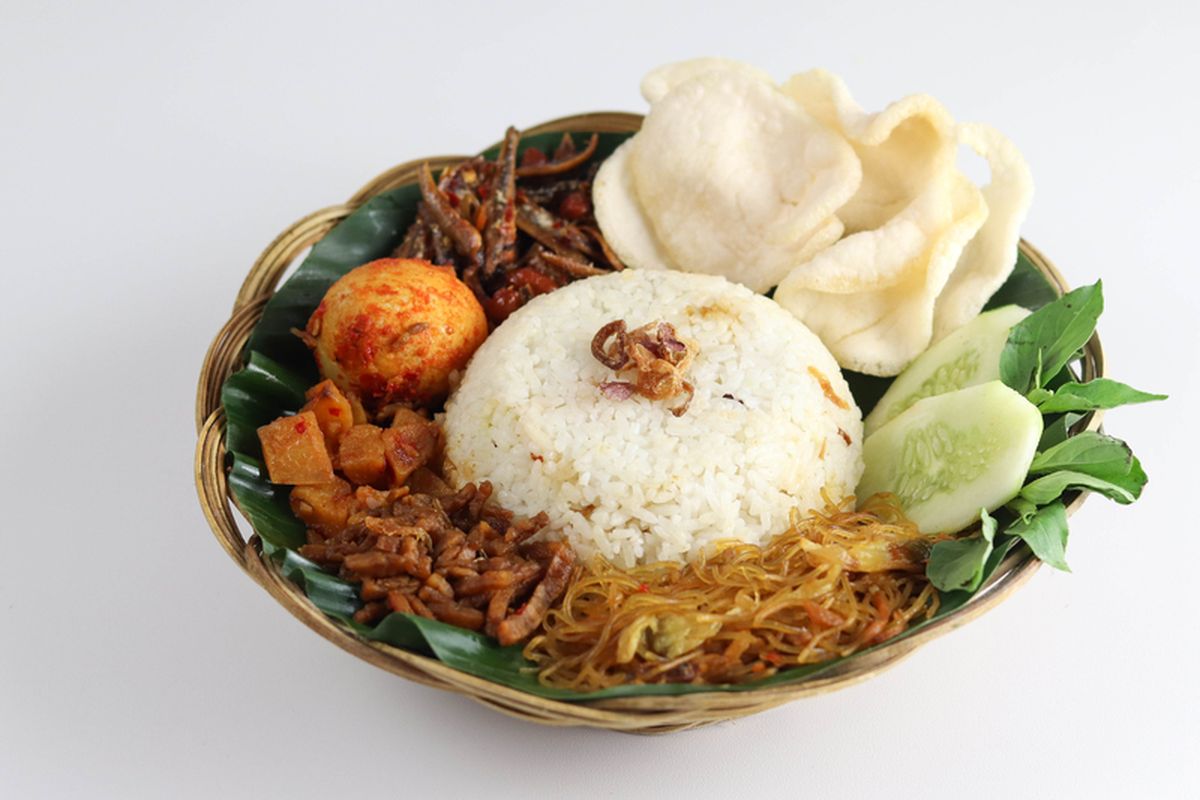 Semangkuk nasi uduk dengan lauk lengkap dan sambal kacang.