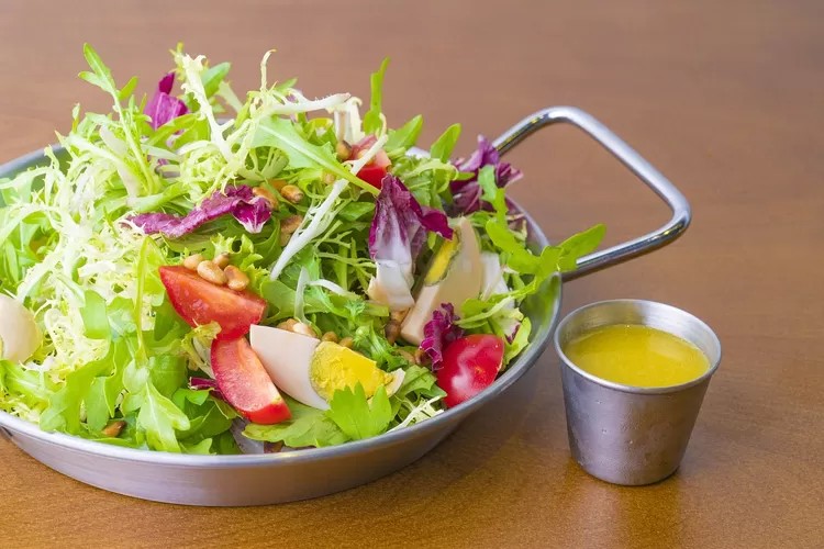 Semangkuk salad segar dengan berbagai sayuran dan protein di meja cafe.