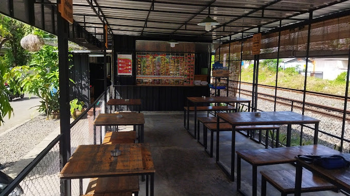 Meja cafe di samping jendela dengan pemandangan kereta api yang melintas.