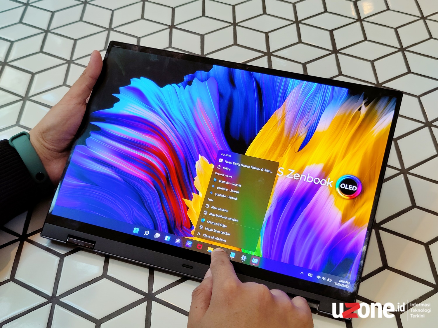 Gambar ASUS ZenBook 14 Flip OLED dalam mode tablet atau mode tenda di meja, menampilkan keserbagunaannya, dengan latar belakang Istana Plaza Bandung.