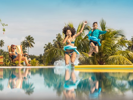 Gambar kolam renang resor mewah dengan keluarga sedang menikmati.