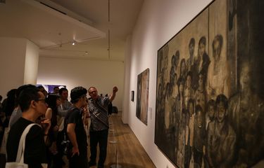 Orang-orang sedang melihat pameran seni di galeri yang terang dan modern.