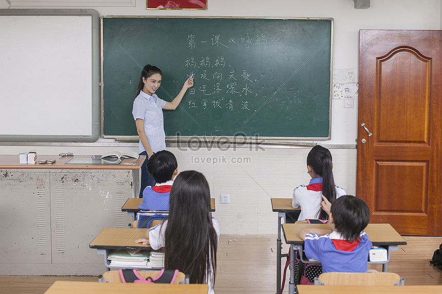 Gambar siswa-siswi belajar menulis aksara Mandarin di kelas dengan bimbingan guru.