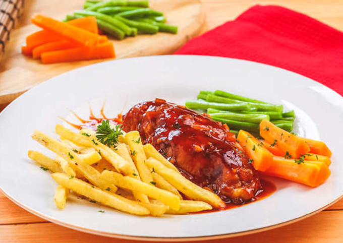Piring steak dengan kentang goreng dan saus yang menggugah selera.