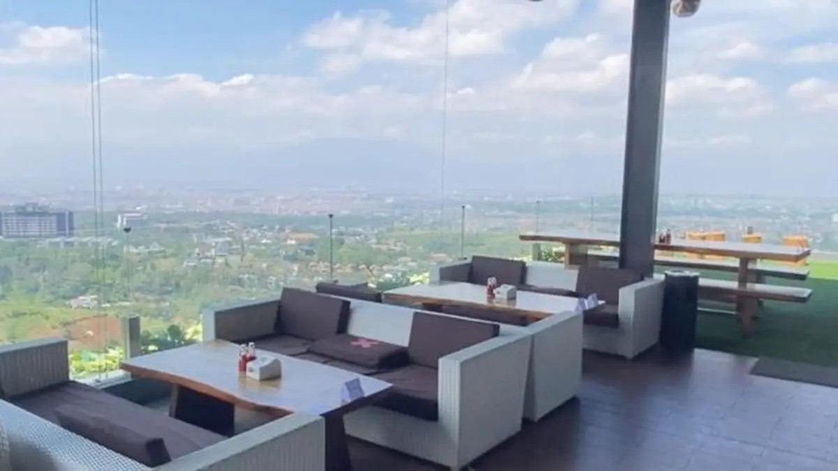 Interior kafe mewah dengan jendela besar menampilkan pemandangan kota Bandung.