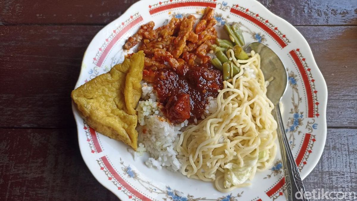 Meja makan sederhana di warung nasi campur dengan berbagai pilihan lauk pauk.