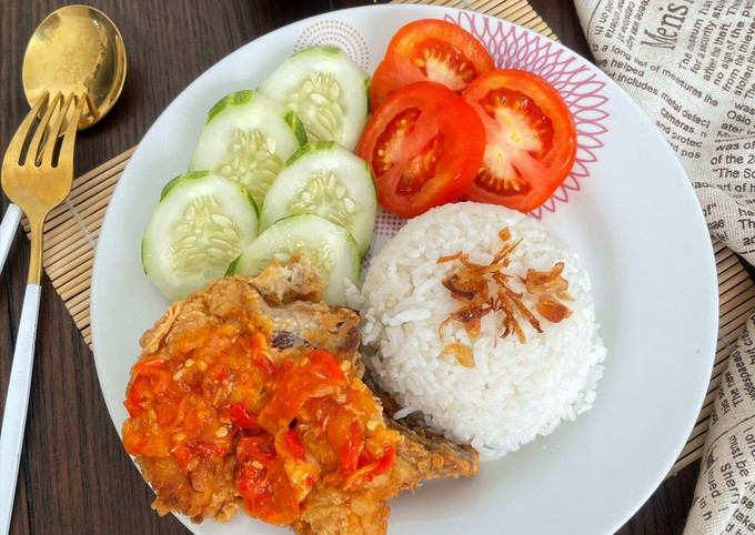 Piring berisi ayam geprek dengan sambal yang melimpah, nasi hangat, dan lalapan segar.