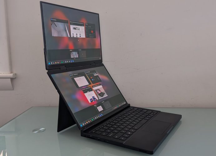 Laptop dengan dua layar terbuka, menampilkan aplikasi berbeda di layar utama dan layar sekunder.