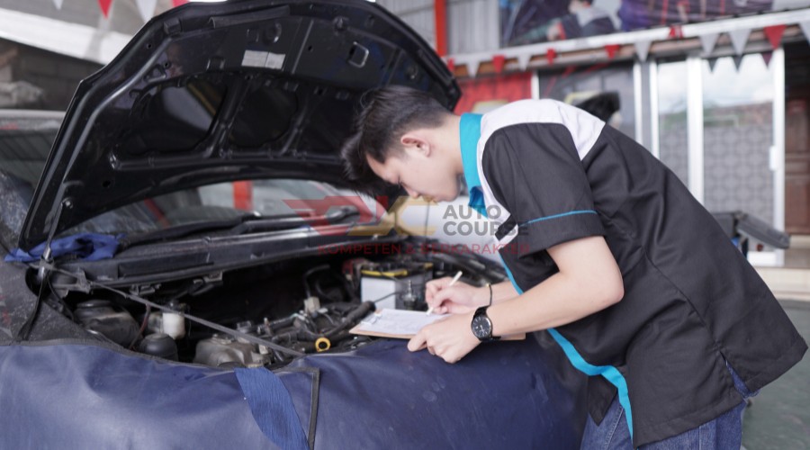 Mekanik sedang memeriksa mesin diesel di sebuah bengkel yang terorganisir.