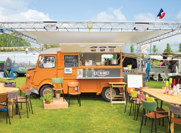 Berbagai food truck berwarna-warni berjajar di sebuah event outdoor dengan pengunjung yang ramai.