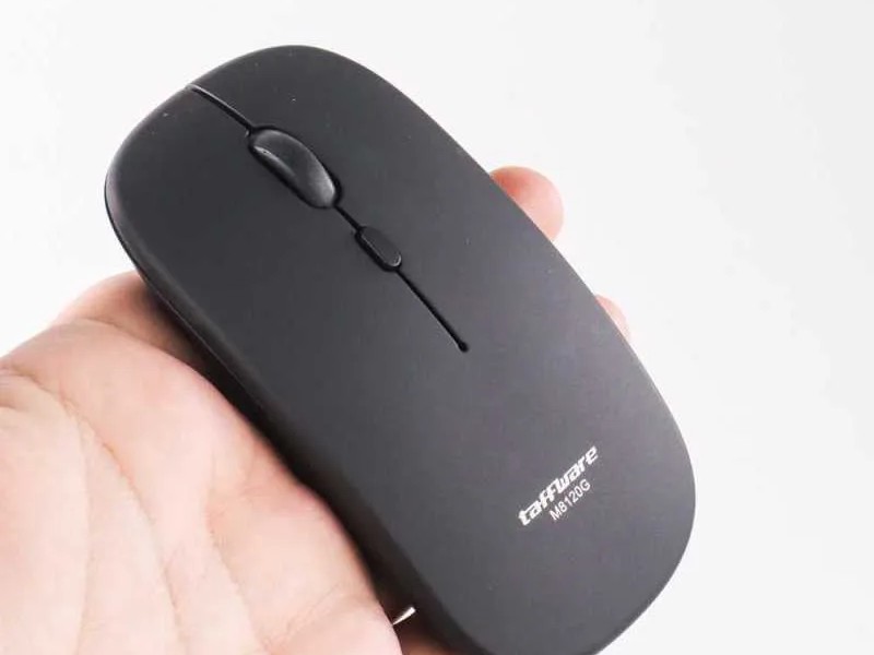 Gambar mouse Bluetooth ramping dan minimalis di atas meja bersih di samping laptop ramping dan tipis, menonjolkan pengaturan bebas kabel dan bebas kekacauan.
