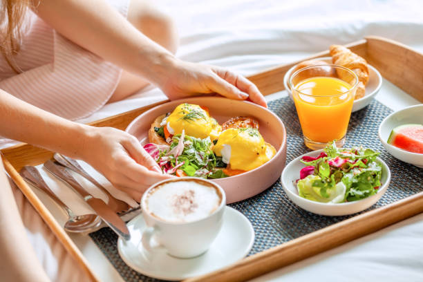 Piring berisi egg benedict dengan kopi dan jus di meja kafe.