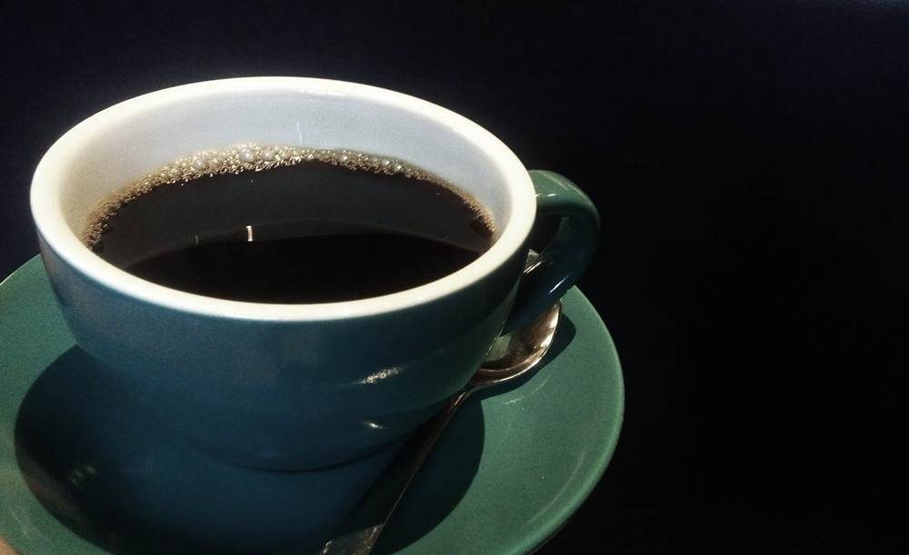 Segelas kopi jahe panas dengan uap mengepul di malam hari.