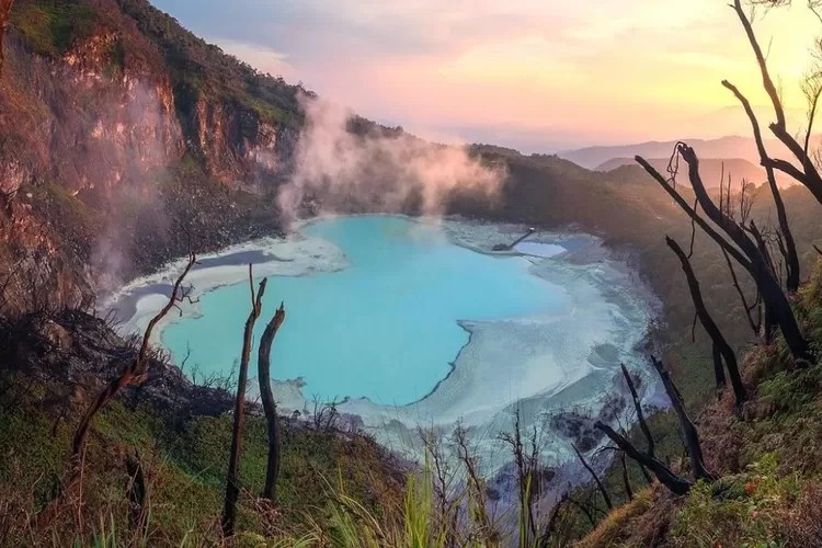 Pemandangan Kawah Putih Ciwidey dengan danau berwarna pirus dan kabut tipis.