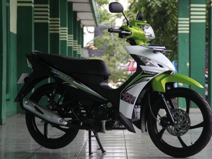 Gambar Suzuki Smash FI diparkir di area perumahan atau pasar lokal di Rawamangun, menekankan kepraktisan dan penggunaan umumnya dalam kehidupan sehari-hari masyarakat Indonesia.