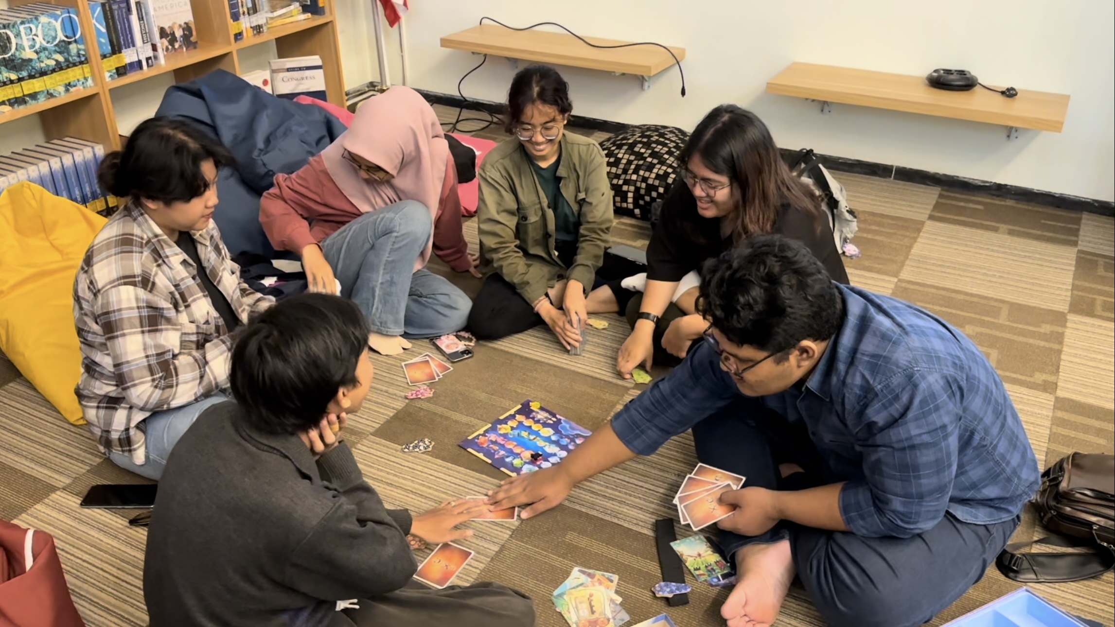 Gambar siswa-siswi bermain board game edukasi di kelas, terlihat antusias dan berinteraksi.