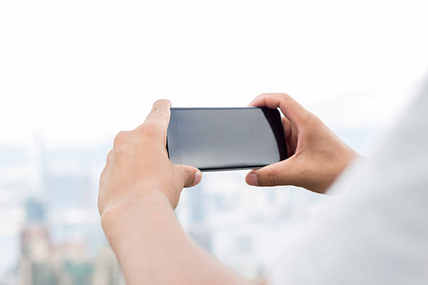 Tangan memegang smartphone dengan aplikasi media sosial terbuka, di latar belakang ada siluet keramaian orang atau peta wilayah.