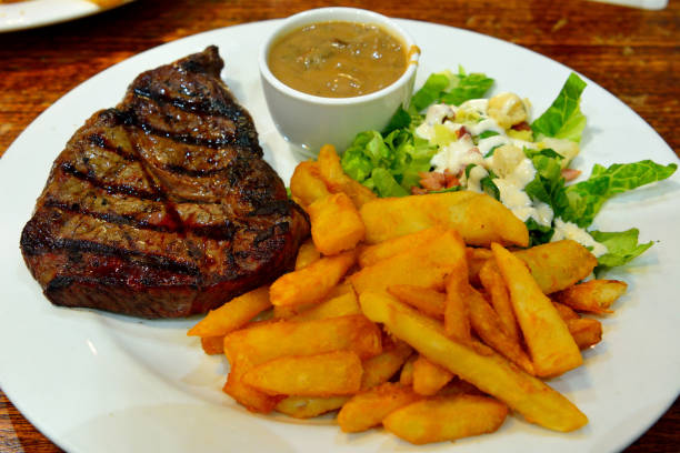 Sepiring dry-aged steak dengan kentang goreng dan saus di restoran steak.