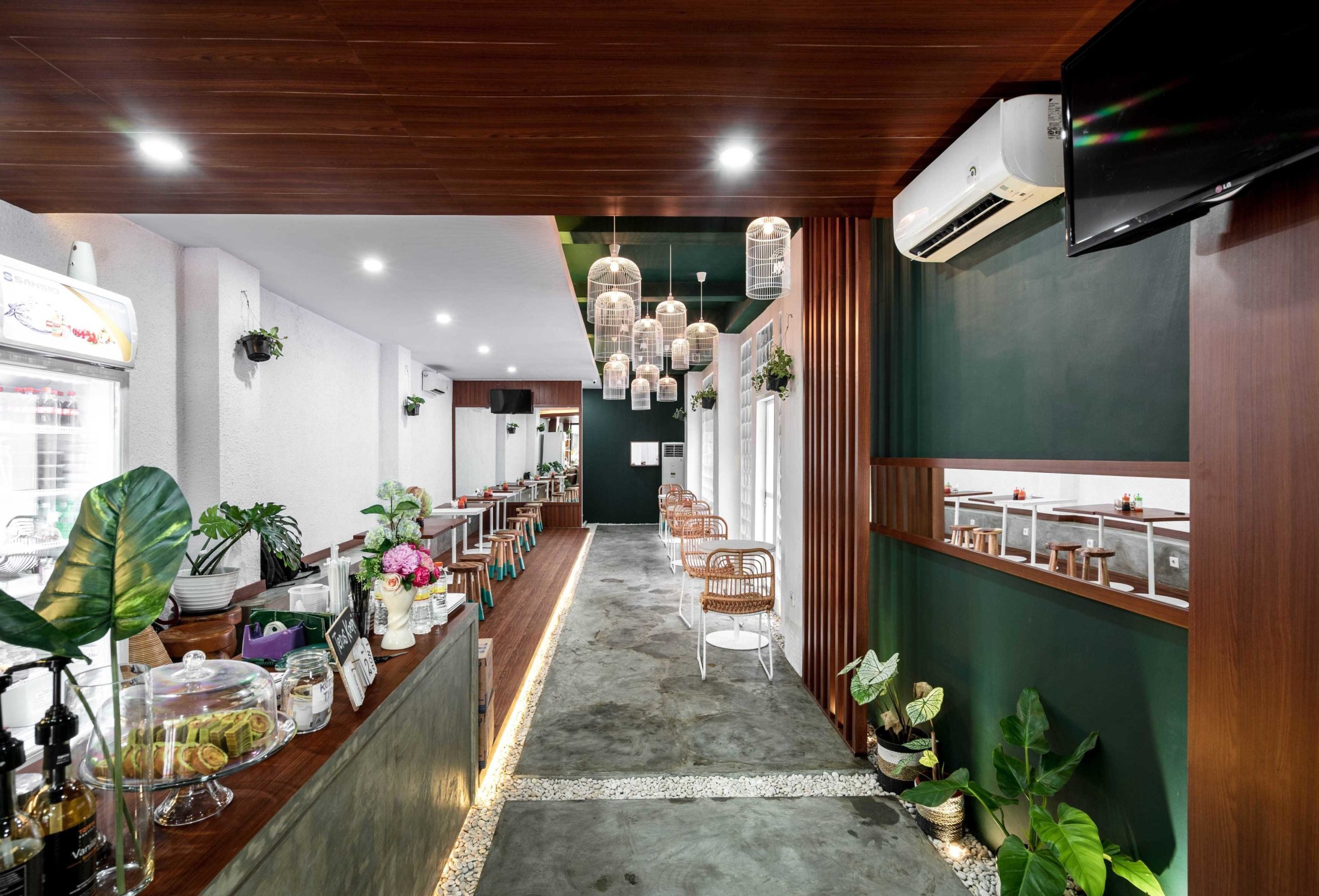 Interior cafe dengan desain estetik, tanaman hias, dan pencahayaan hangat.