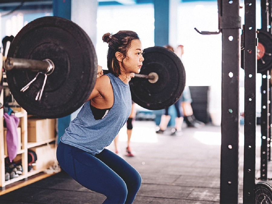 Seseorang sedang melakukan squat dengan barbel di gym modern.