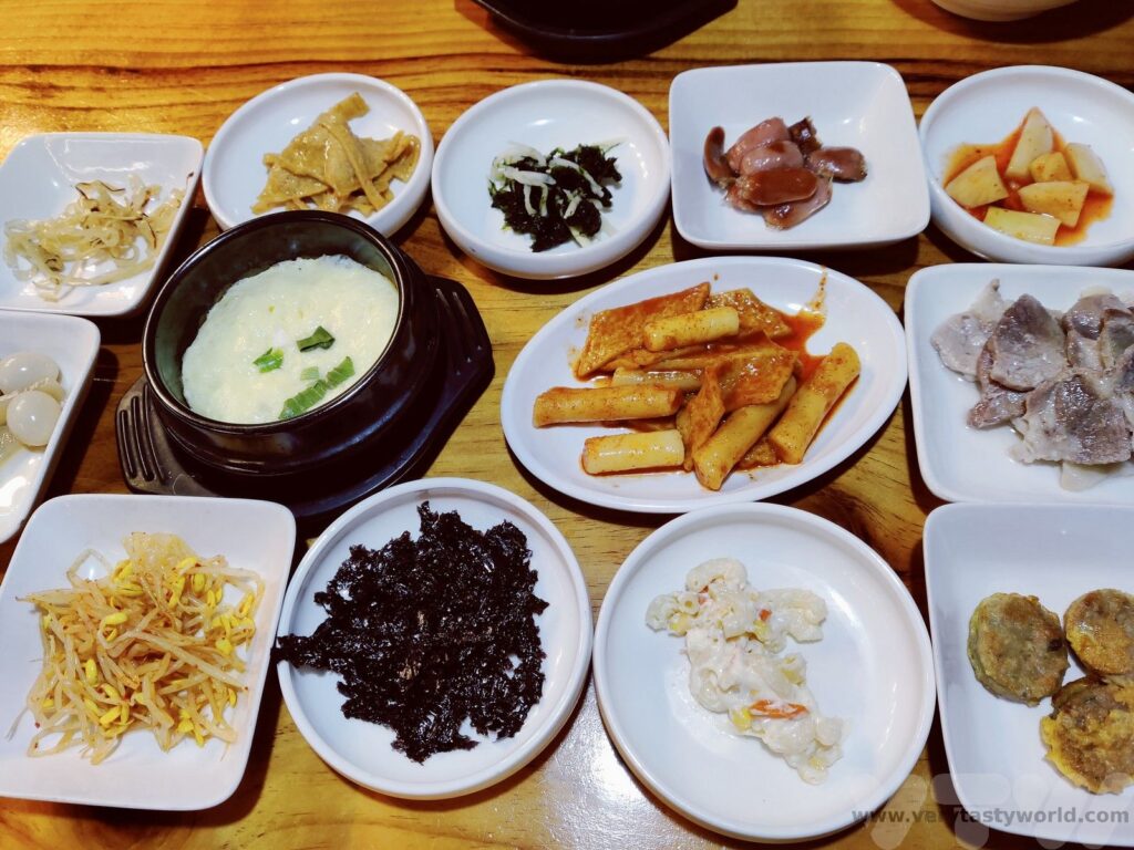 Meja makan dengan hidangan Korean BBQ, banchan, dan kimchi.
