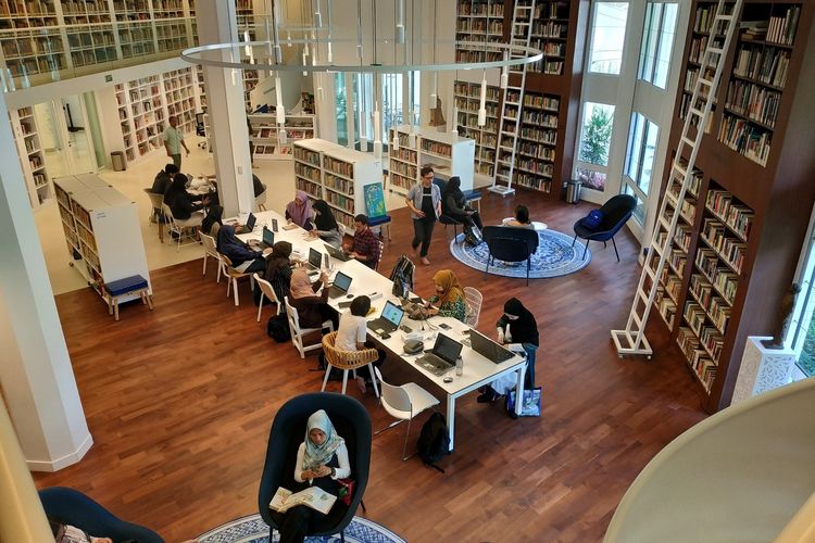 Gambar interior perpustakaan komunitas yang nyaman dengan orang-orang berdiskusi.