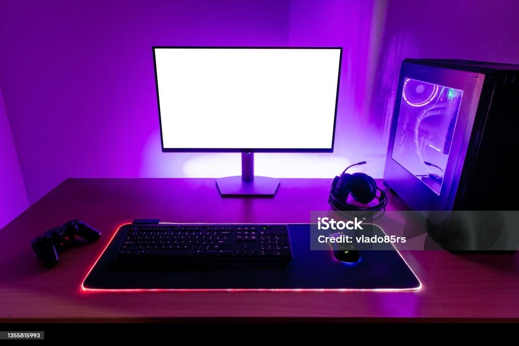 Meja gaming dengan keyboard RGB, mouse, dan headset gaming.