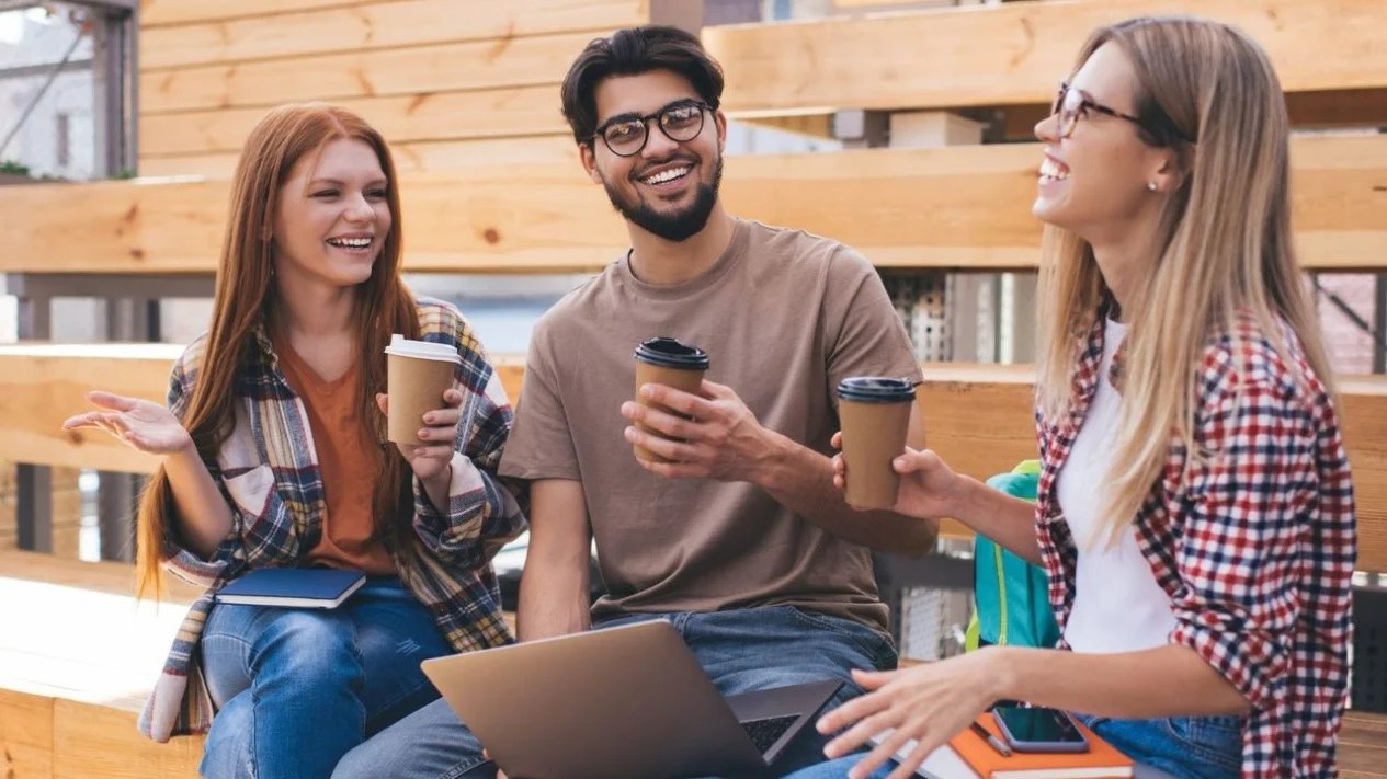 Interior cafe dengan orang-orang sedang bekerja menggunakan laptop.
