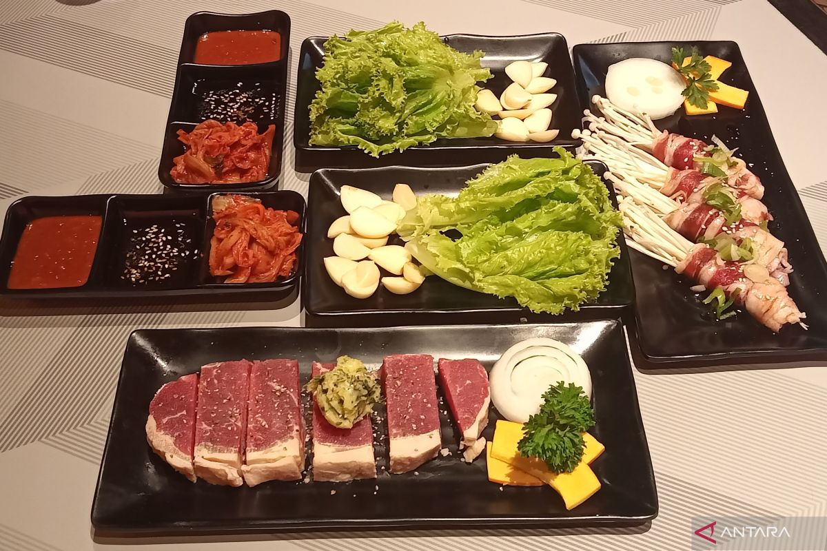 Meja restoran All You Can Eat dengan berbagai potongan daging mentah yang siap dibakar dan aneka side dish Korea.