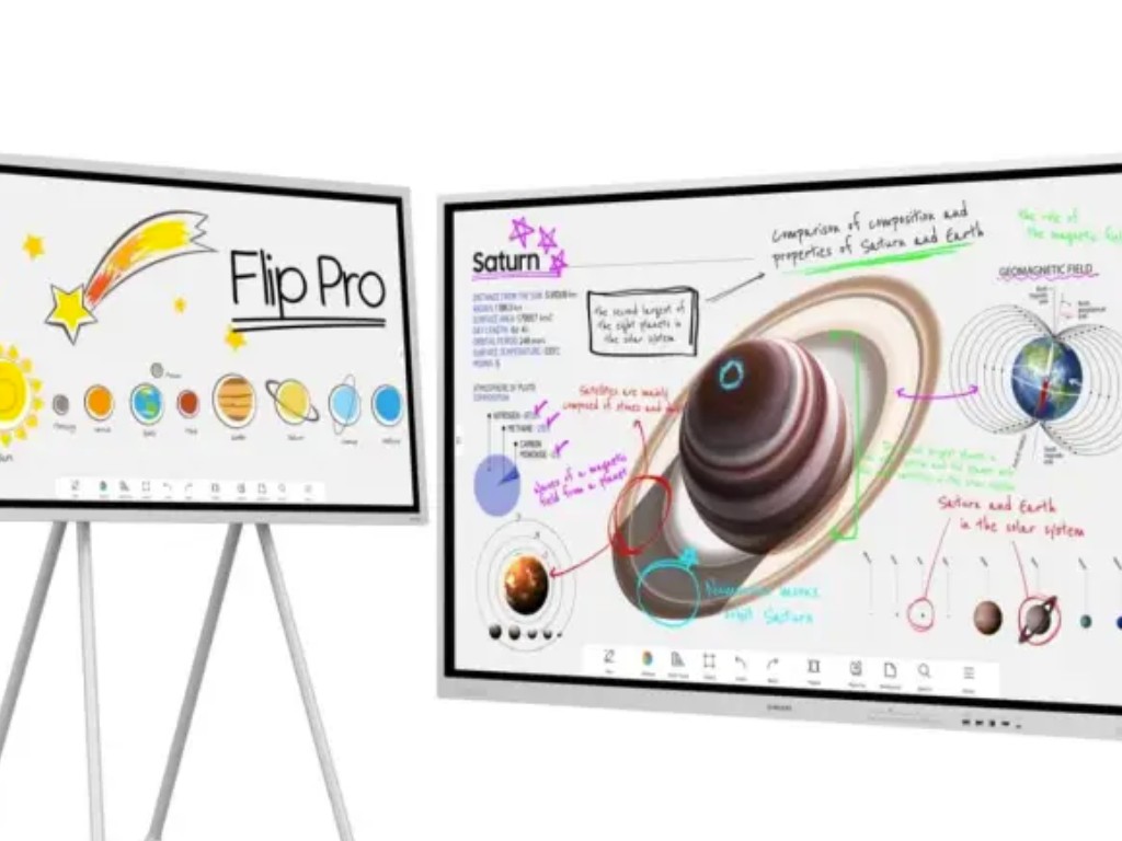 Gambar layar Samsung Professional Display berukuran besar di ruang konferensi modern, menampilkan presentasi yang sedang ditampilkan, dengan orang-orang berkolaborasi di sekitar meja, menekankan pengg